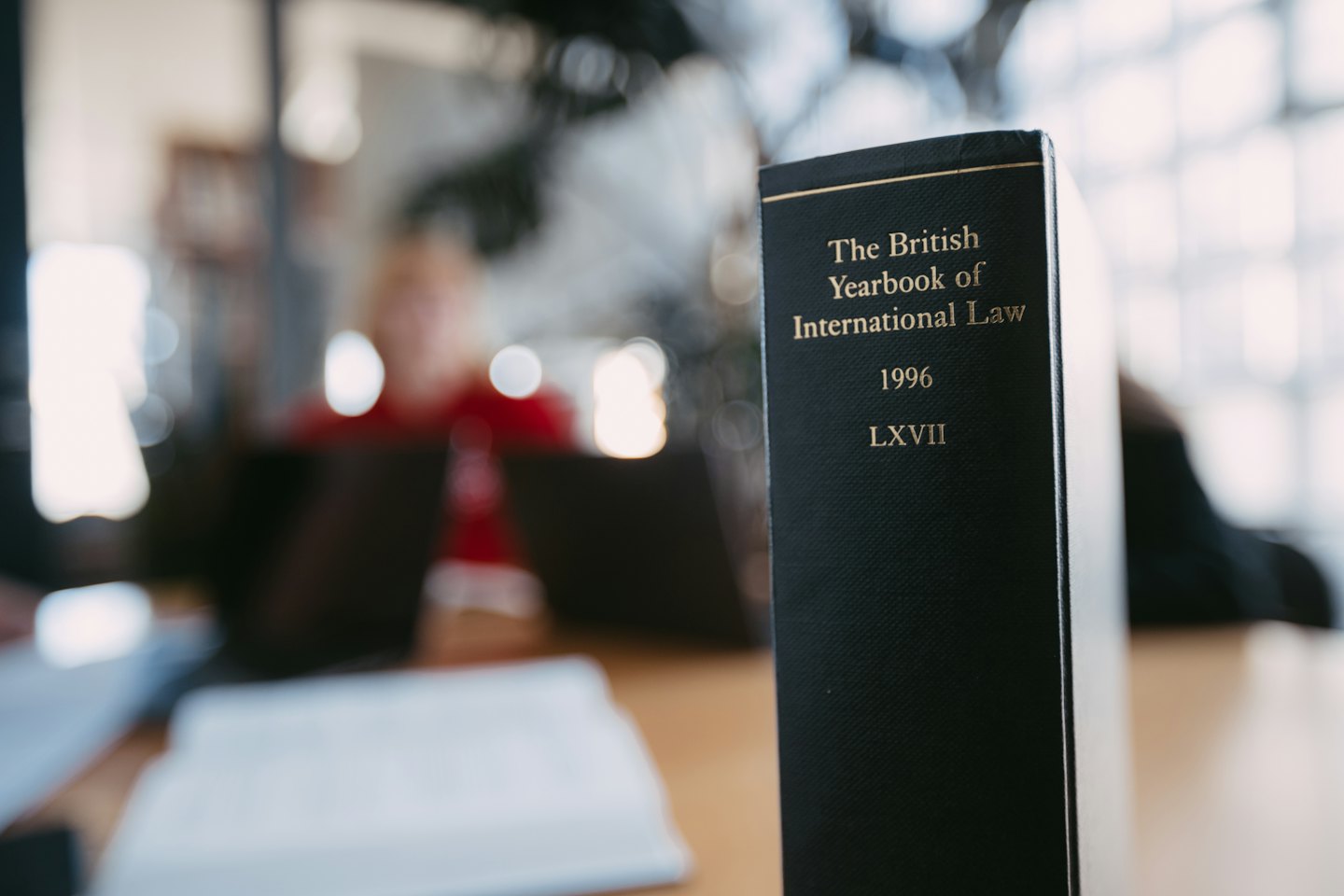 A legal textbook stands upright on a wooden table.