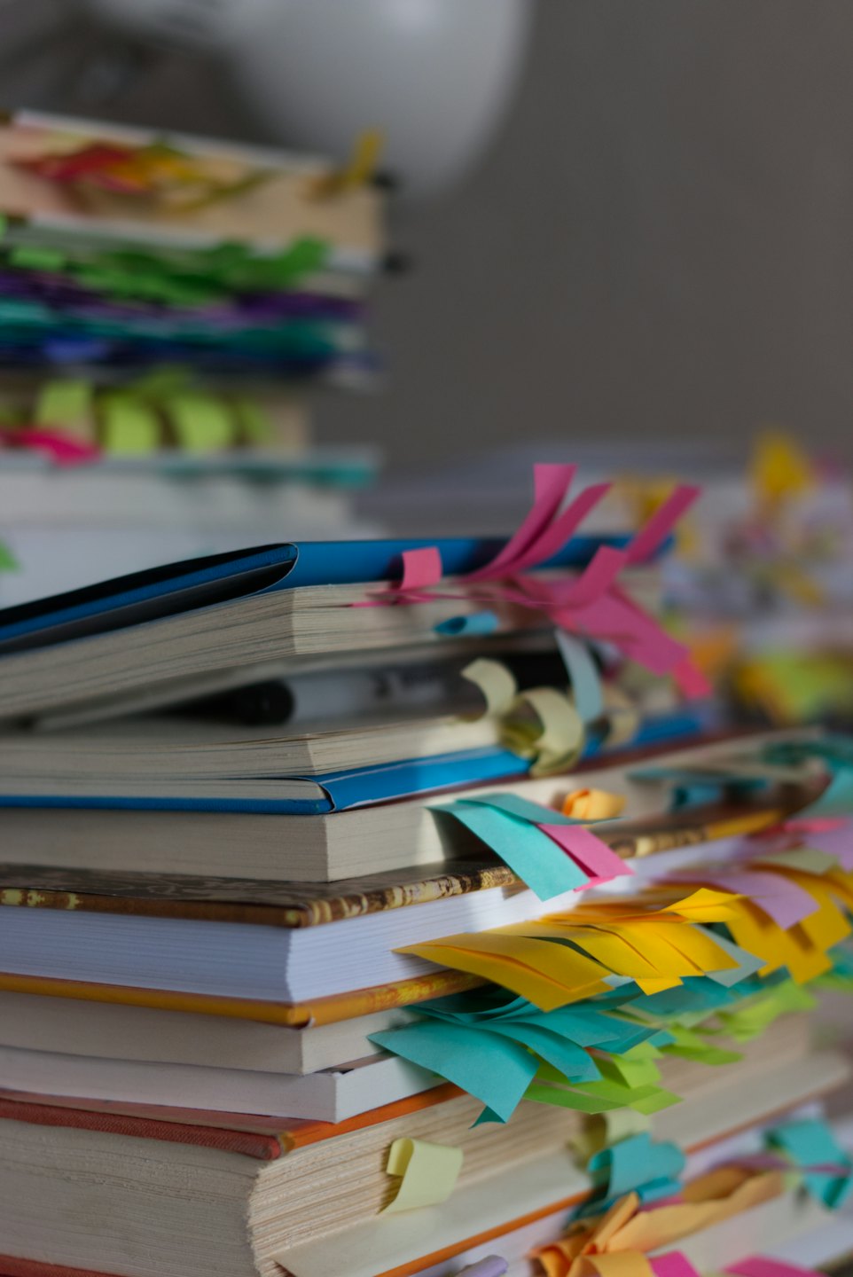Stacks of books and notebooks covered in colorful sticky notes.